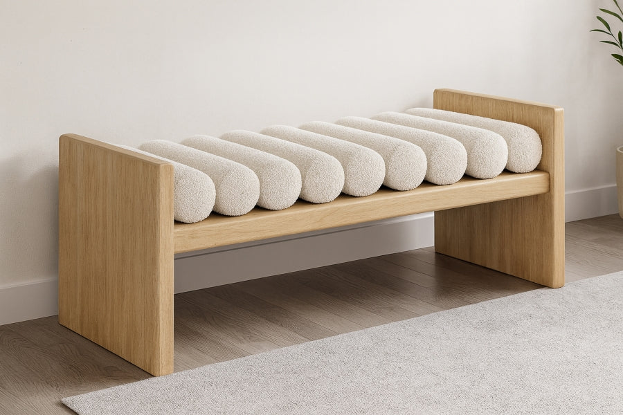 Wrenley boucle upholstered bench with natural wood H-shaped frame and nine cream cushion rolls.