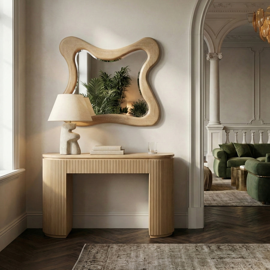 Natural wood Oro wall mirror with an organic wavy frame above a fluted console table.