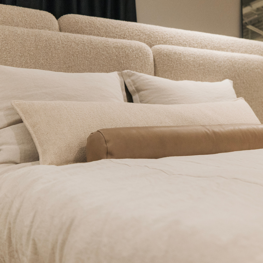 Beige pillows and bedding on a bed with a neutral background
