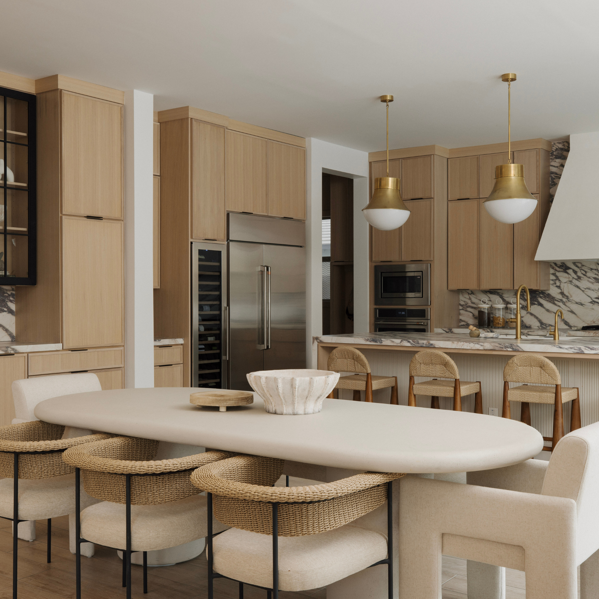 Modern white concrete dining table with an oval top, surrounded by light-colored chairs in a contemporary kitchen.