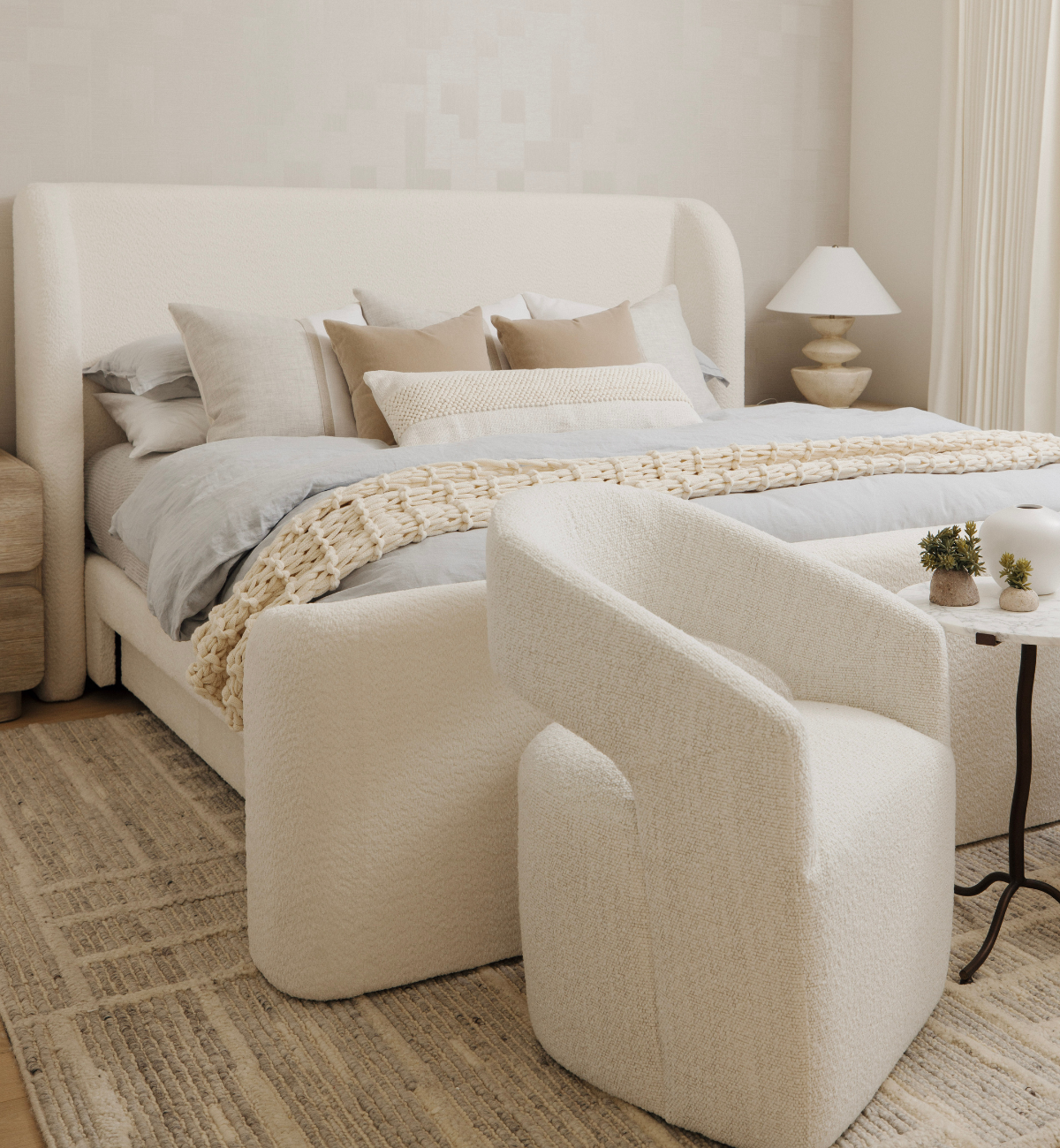 Modern bedroom with a bed, swivel chair, and side table.