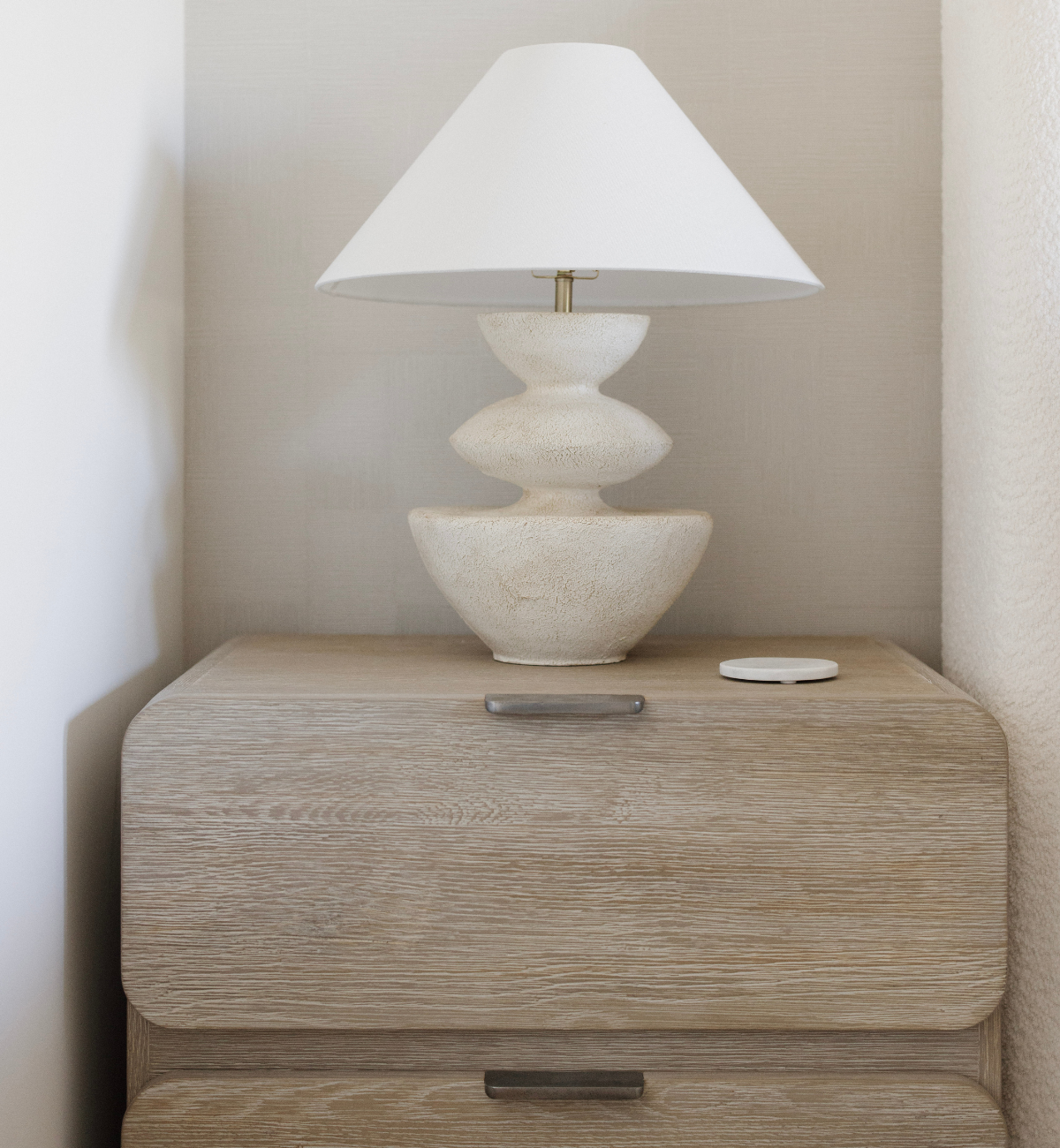 Beige nightstand with a decorative lamp on a neutral wall background
