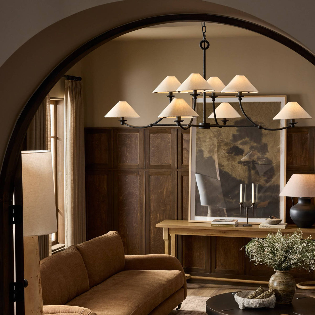 Dark wood console styled with a ceramic lamp, sculptural vessels, and tall flowering branches.