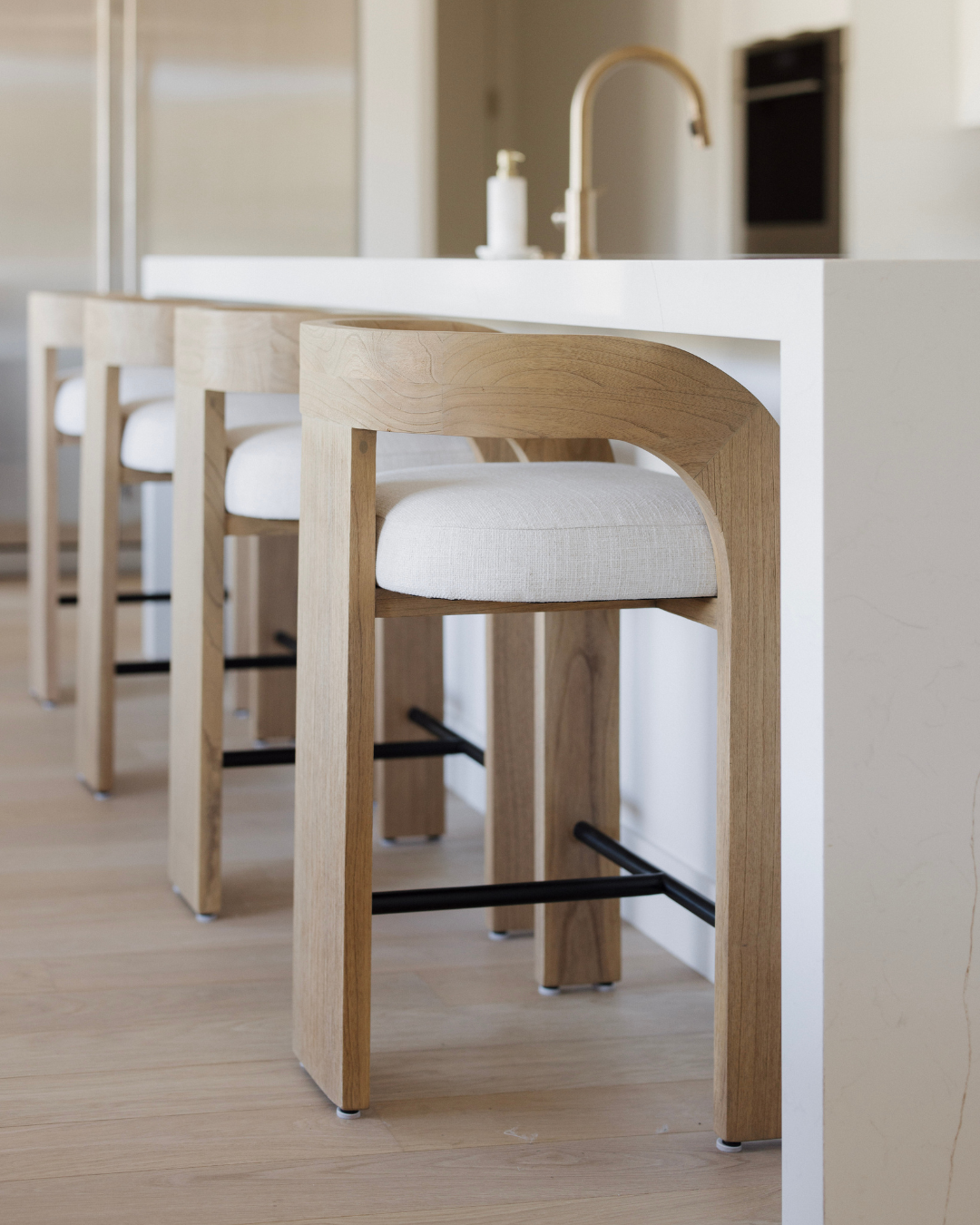 Wooden bar stools with white seats in a modern kitchen setting.