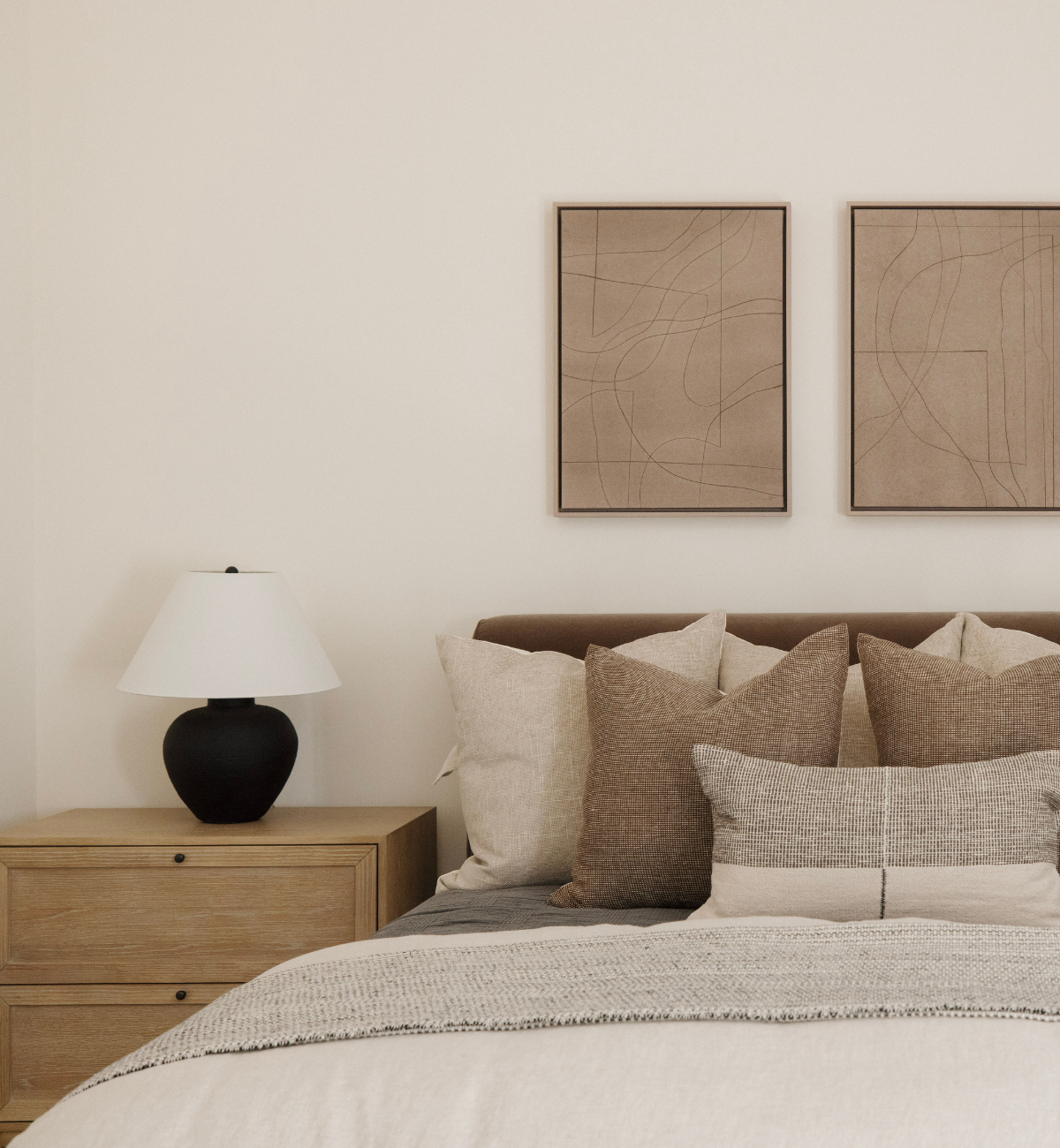 Neatly made bed with pillows and a lamp on a nightstand in a bedroom setting.