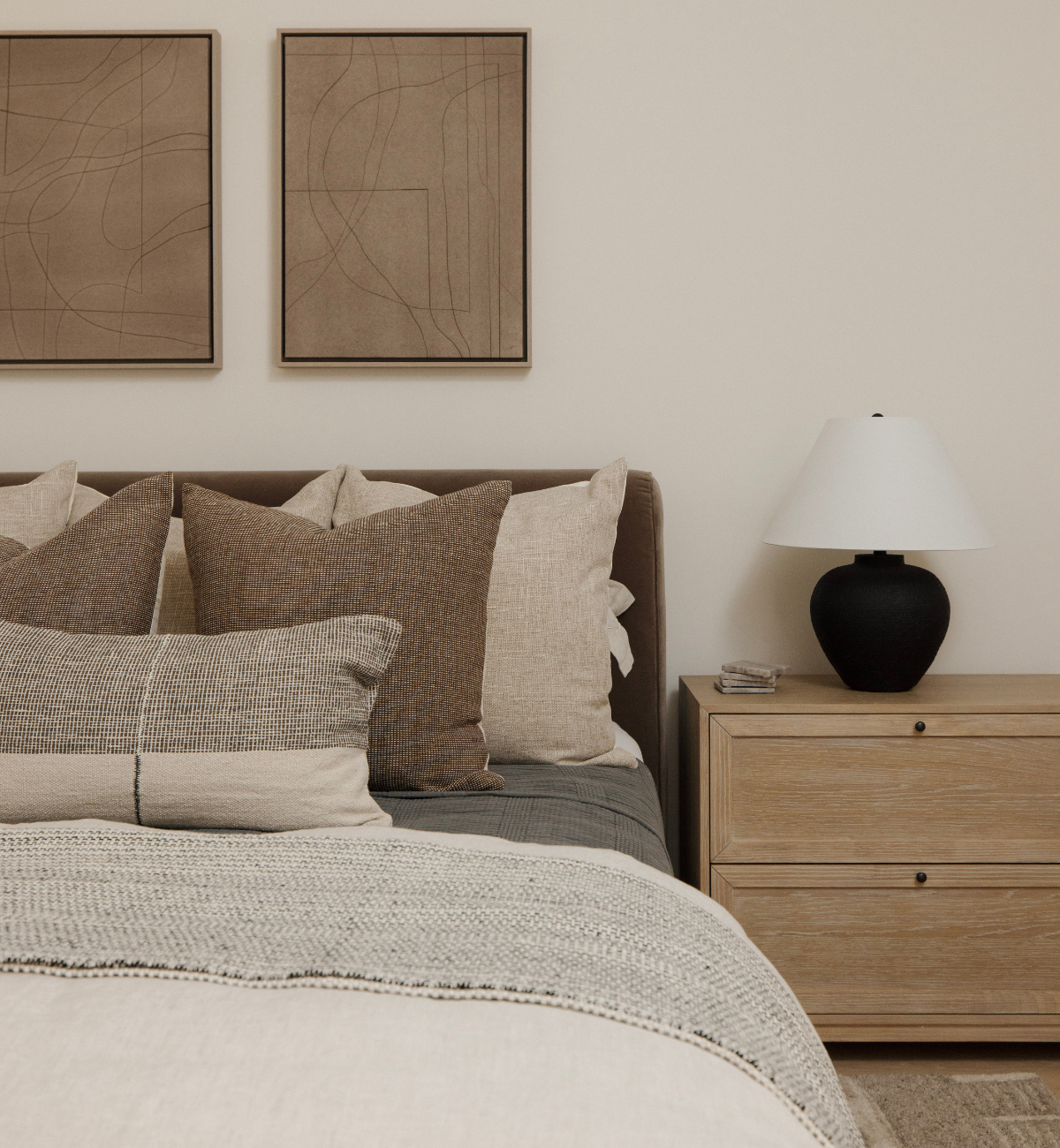 Neatly made bed with pillows and a lamp on a nightstand in a bedroom setting.