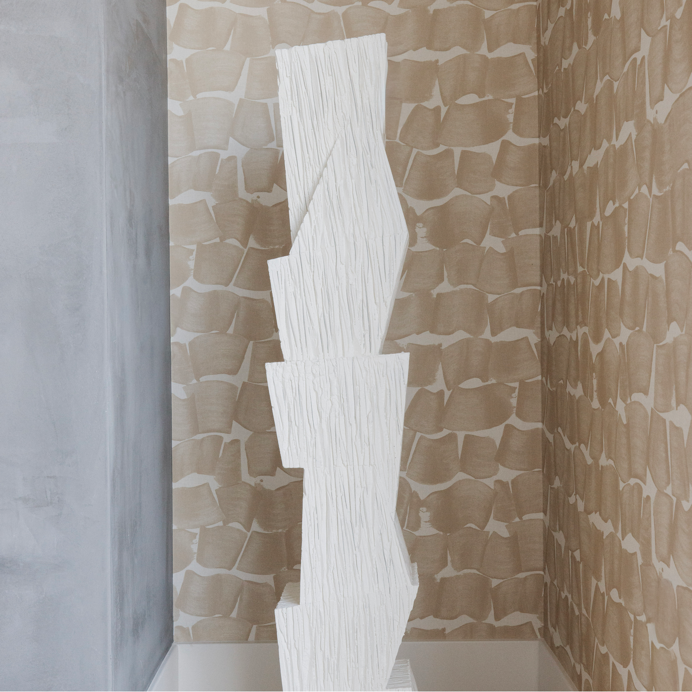 White abstract sculpture against a textured wallpaper wall