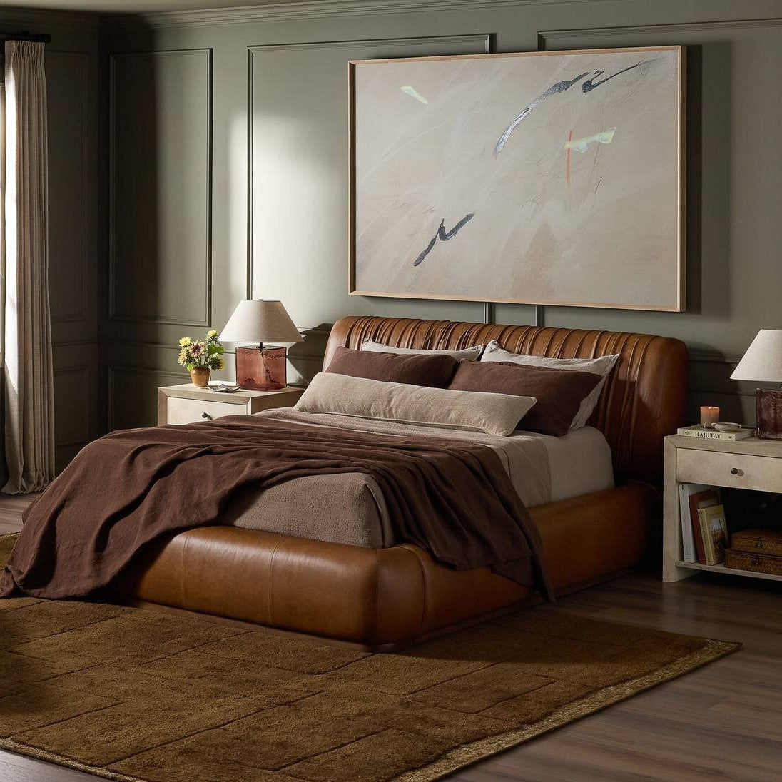 Flora hand-knotted rug in a bedroom with a leather bed and dark wood dresser, by StyleMeGHD.