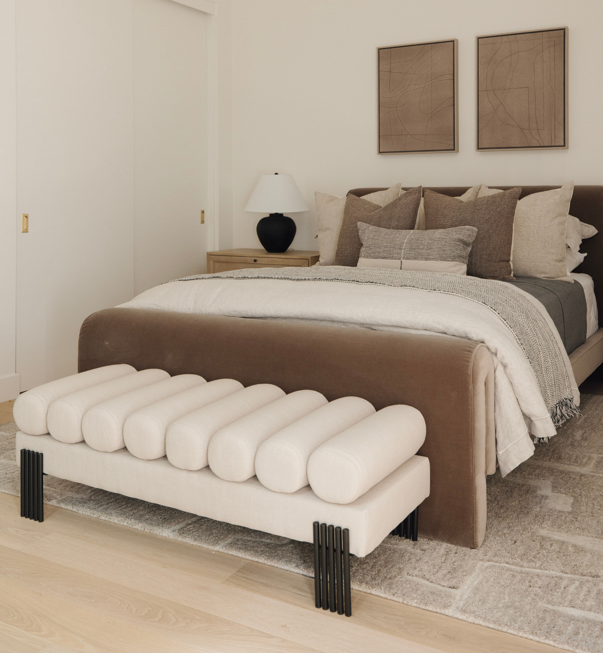 Modern bedroom with a bed and bench in a neutral color scheme.