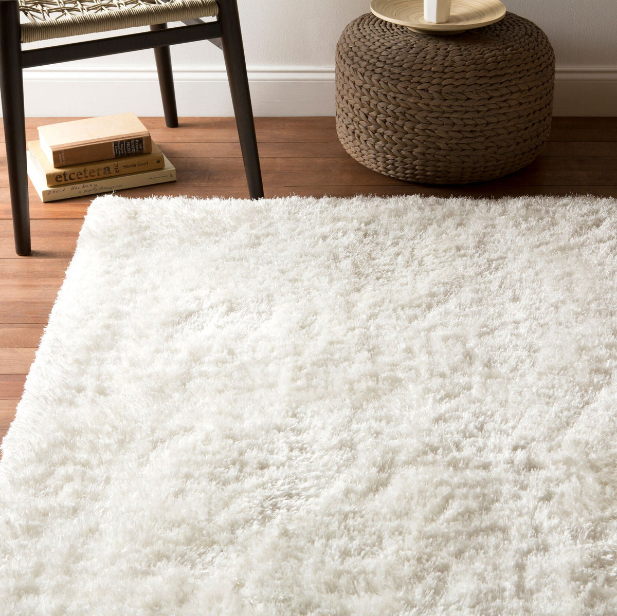 Greer handmade rug, a plush ivory shag, beneath a woven pouf and wood chair, by StyleMeGHD.