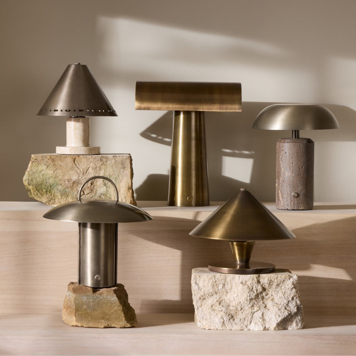 Five table lamps in brass and stone finishes arranged on stone blocks