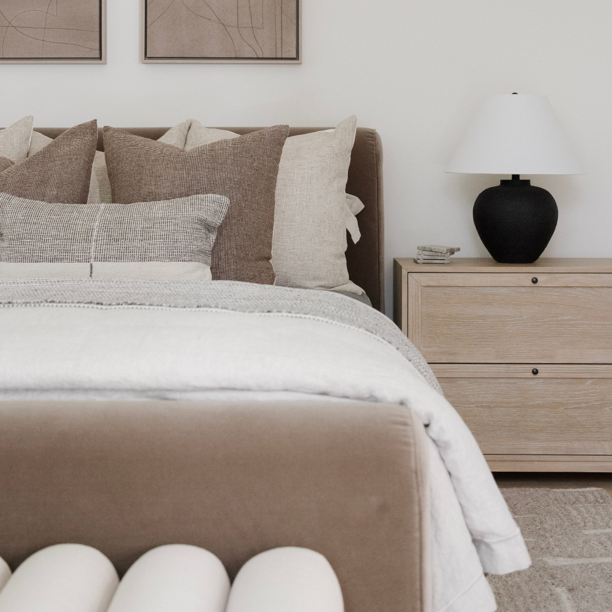Neatly made bed with beige and brown bedding in a bedroom setting.