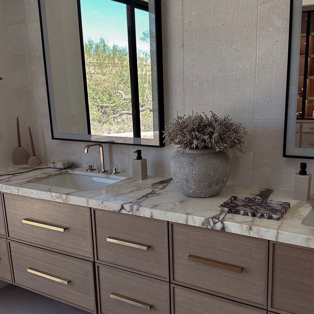 Bathroom vanity with marble countertop, large mirror, and decorative elements.