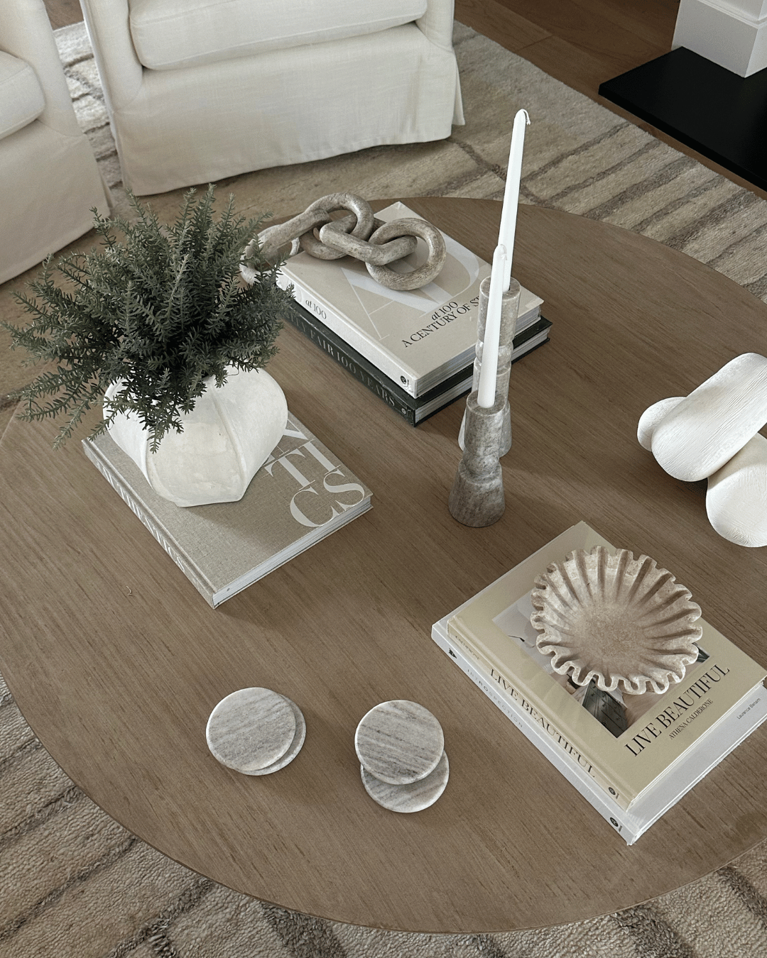 Decorative items on a wooden coffee table including books, a candle, and small plants.