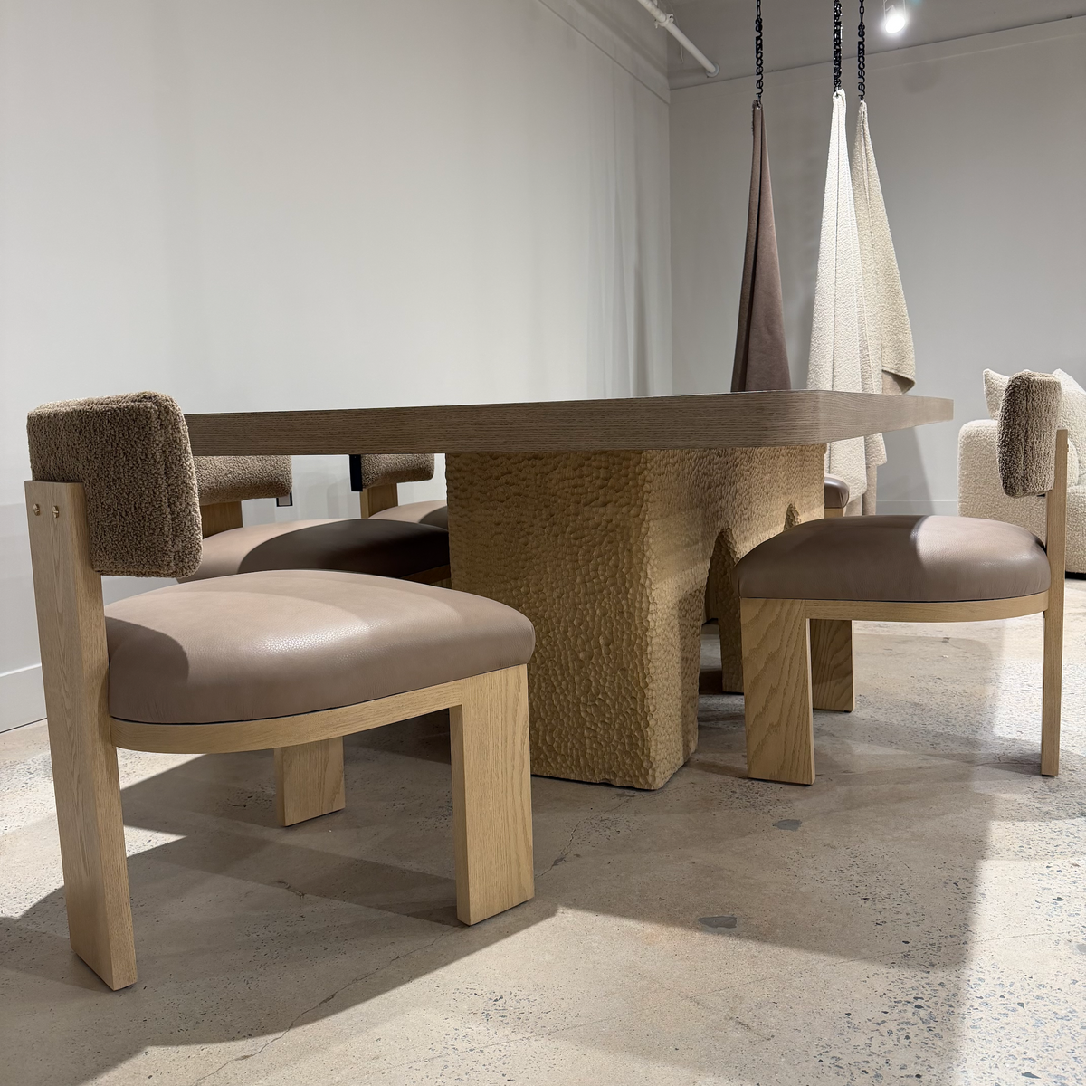 Ocotillo dining chairs with brown boucle back cushions and taupe leather seats around a sculptural dining table